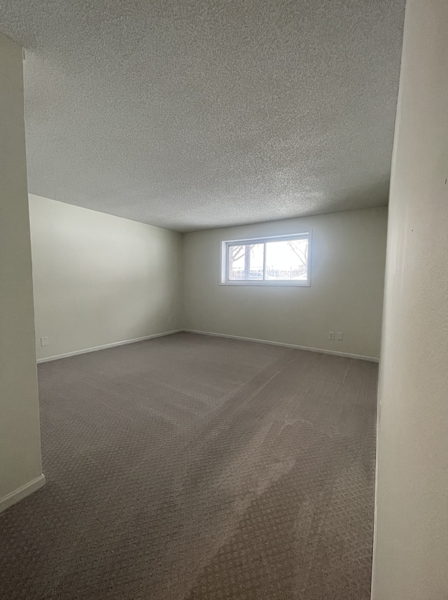 empty room featuring dark carpet and a textured ceiling