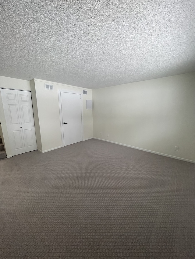 unfurnished bedroom with a textured ceiling and dark carpet