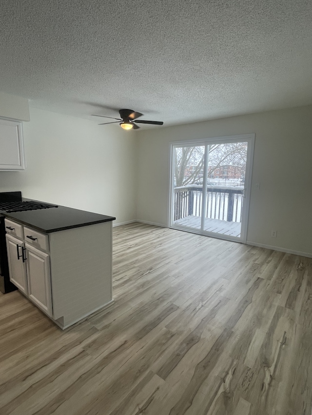 unfurnished living room featuring ceiling fan, light hardwood / wood-style floors, and a textured ceiling