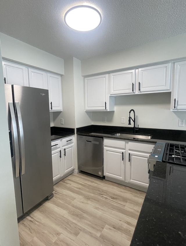 kitchen with light hardwood / wood-style floors, white cabinetry, sink, and appliances with stainless steel finishes