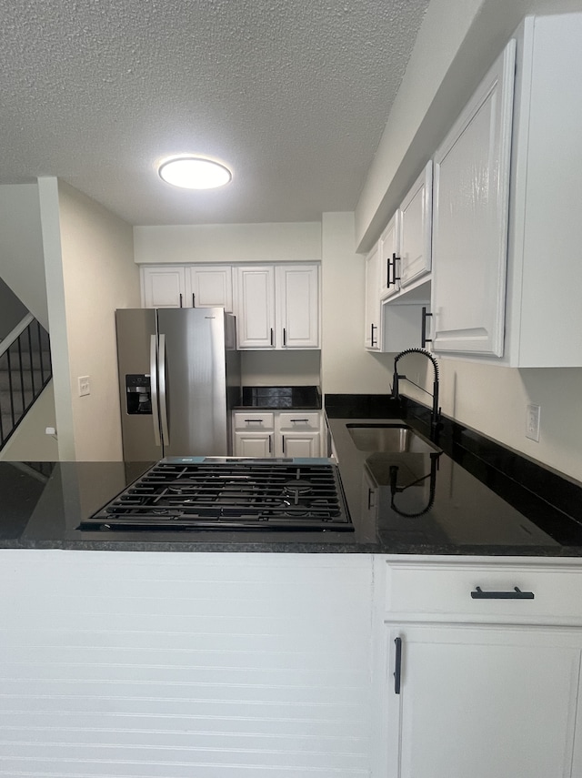 kitchen with white cabinetry, sink, gas stovetop, stainless steel fridge, and a textured ceiling