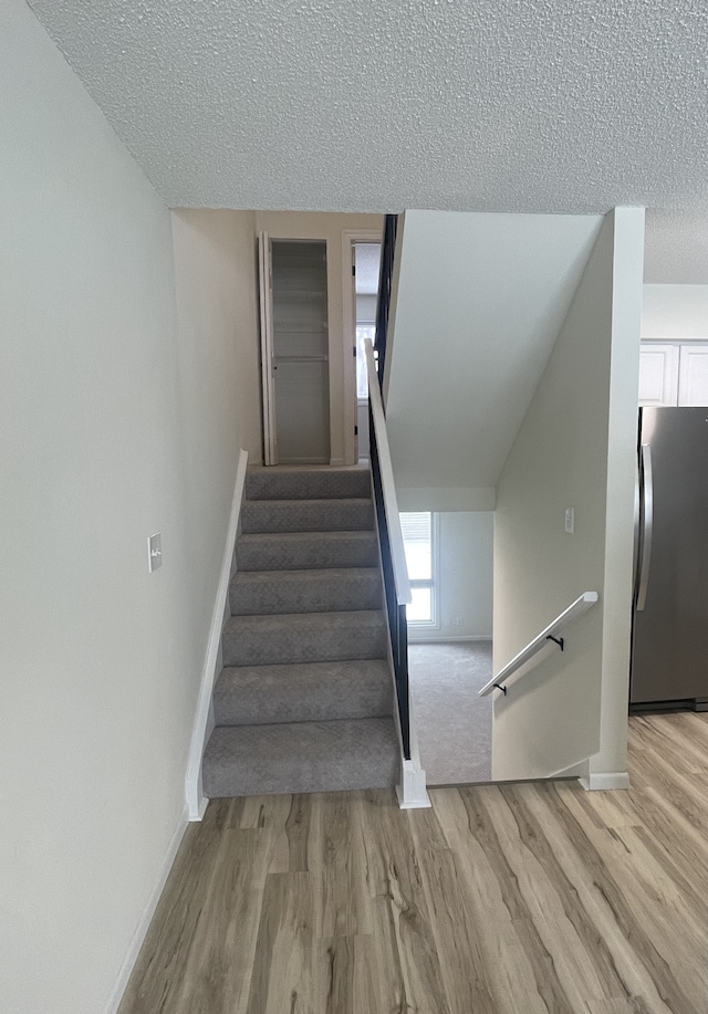 staircase with wood-type flooring and a textured ceiling