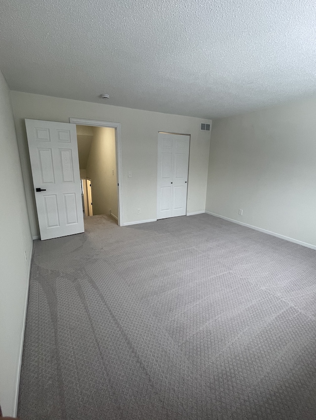 unfurnished bedroom featuring a textured ceiling, carpet floors, and a closet