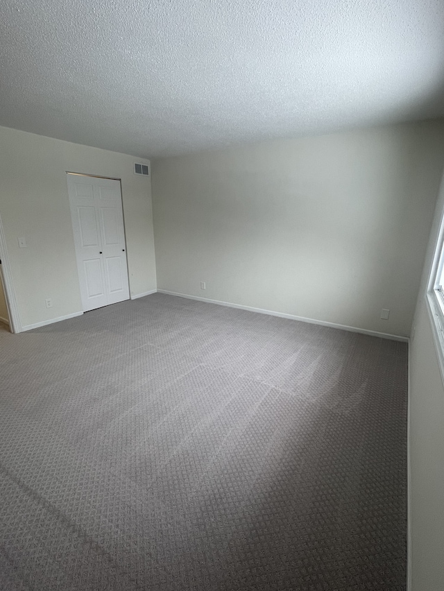 spare room featuring carpet flooring and a textured ceiling