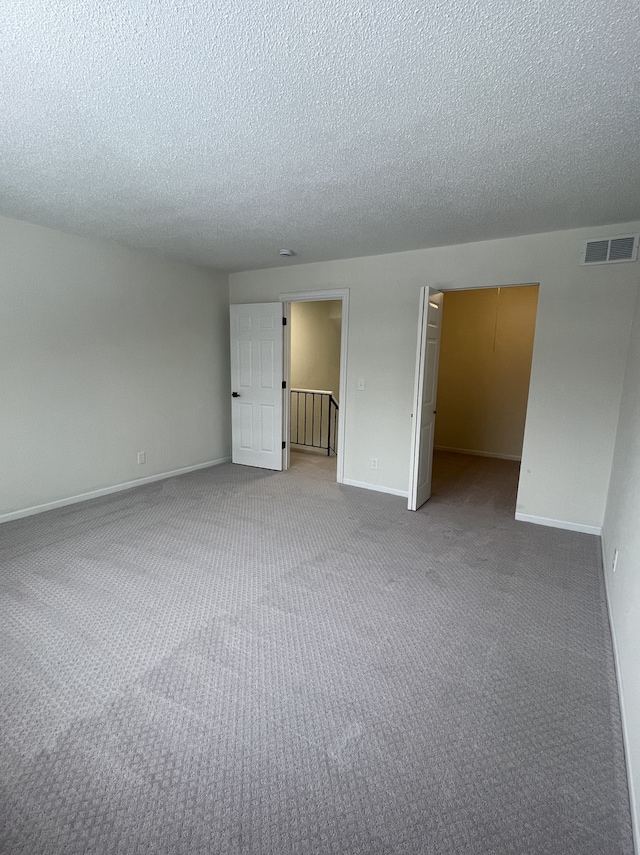 empty room with carpet flooring and a textured ceiling