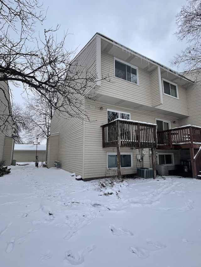 snow covered back of property featuring central air condition unit