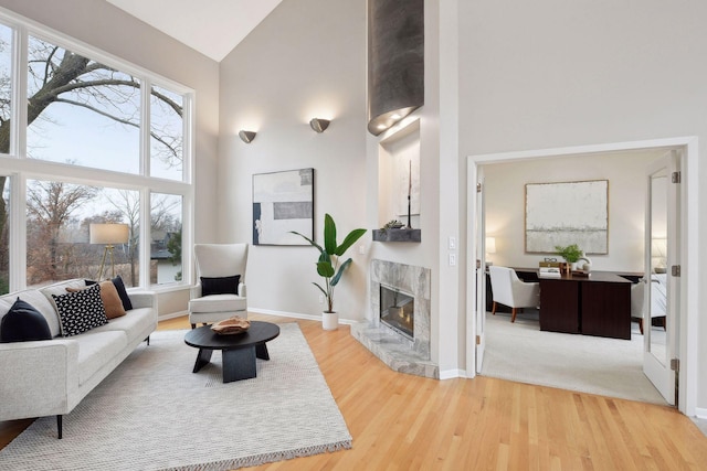 living room with high vaulted ceiling, wood-type flooring, and a high end fireplace