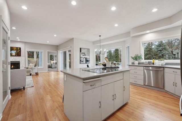 kitchen with white cabinetry, decorative light fixtures, dishwasher, and light wood-type flooring