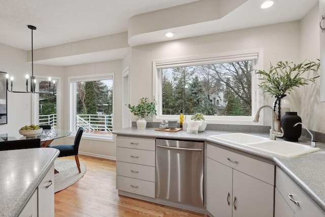 kitchen featuring white cabinetry, stainless steel dishwasher, sink, and light wood-type flooring