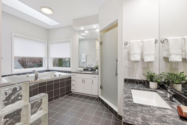 bathroom featuring vanity, tiled bath, tile patterned floors, and a skylight