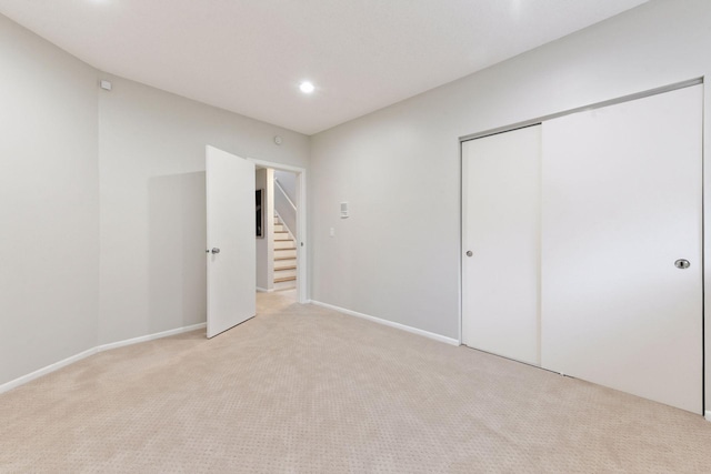 unfurnished bedroom featuring light carpet and a closet