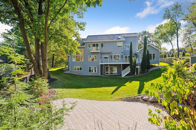 rear view of house featuring a lawn and a deck