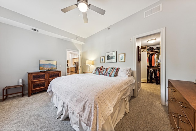 bedroom featuring a spacious closet, light carpet, ceiling fan, and a closet