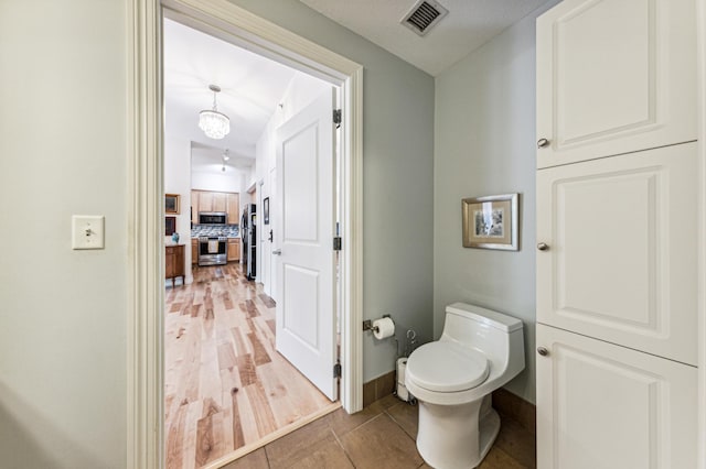 bathroom featuring tasteful backsplash, wood-type flooring, and toilet