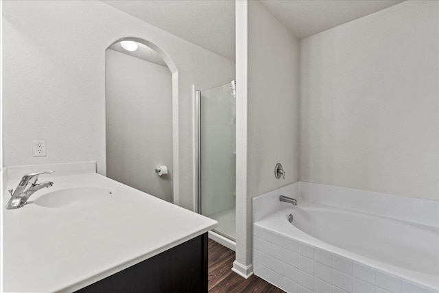 bathroom with hardwood / wood-style floors, plus walk in shower, and vanity