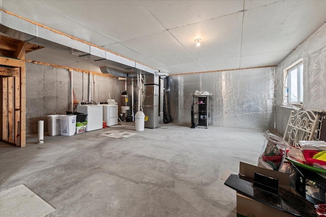 basement featuring water heater, heating unit, and washer and clothes dryer