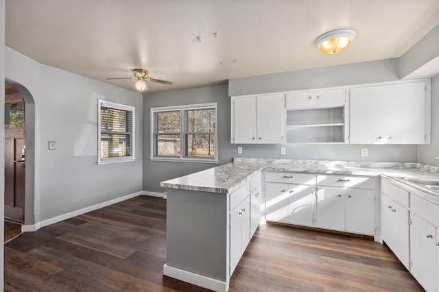 kitchen with arched walkways, a peninsula, ceiling fan, and dark wood finished floors