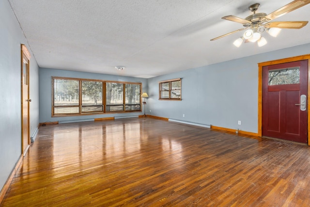 unfurnished living room featuring plenty of natural light, baseboard heating, and hardwood / wood-style flooring