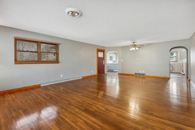 unfurnished living room with hardwood / wood-style floors, visible vents, arched walkways, ceiling fan, and a baseboard heating unit