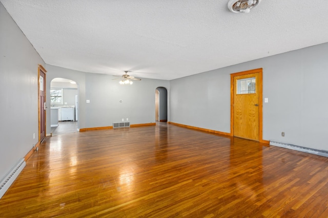 unfurnished living room with arched walkways, visible vents, a baseboard heating unit, and a ceiling fan