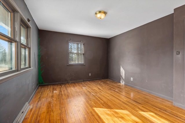 empty room featuring visible vents, a baseboard radiator, baseboards, and hardwood / wood-style flooring