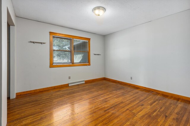 unfurnished room featuring a textured ceiling, baseboards, and hardwood / wood-style flooring