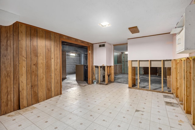 unfurnished room with tile patterned floors, visible vents, and wood walls