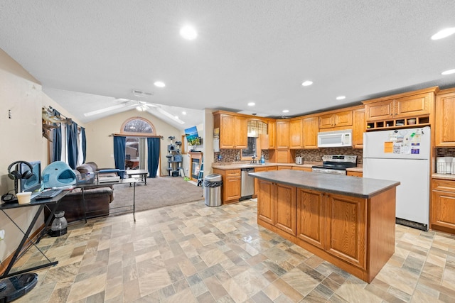 kitchen featuring ceiling fan, backsplash, vaulted ceiling, a kitchen island, and appliances with stainless steel finishes