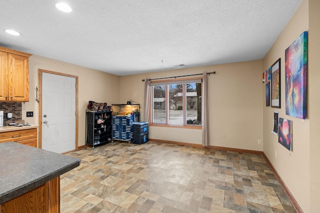 kitchen featuring a textured ceiling and backsplash