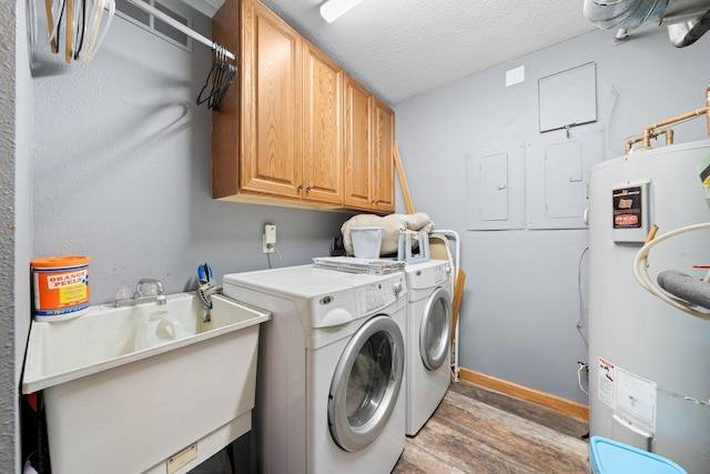 laundry room featuring cabinets, dark wood-type flooring, sink, water heater, and washing machine and dryer