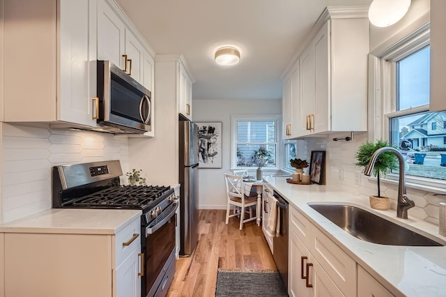 kitchen featuring sink, decorative backsplash, stainless steel appliances, and white cabinets