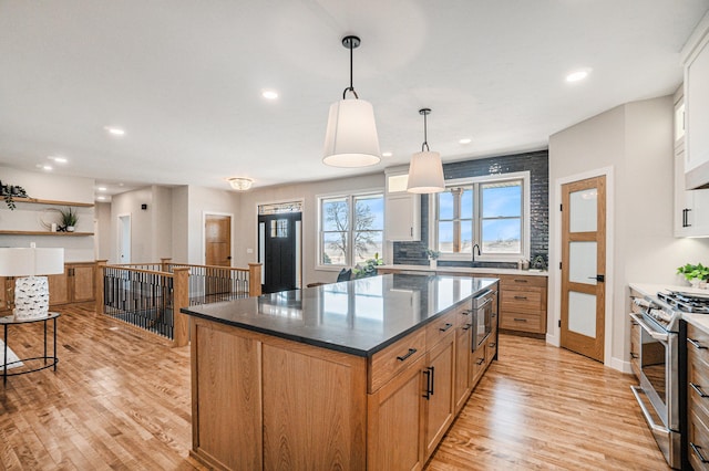 kitchen with white cabinetry, a center island, hanging light fixtures, light hardwood / wood-style floors, and stainless steel range with gas stovetop