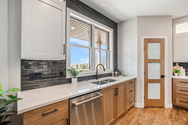 kitchen with backsplash, white cabinetry, sink, and stainless steel dishwasher