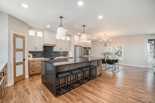 kitchen featuring white cabinets, stainless steel fridge, hanging light fixtures, and a spacious island