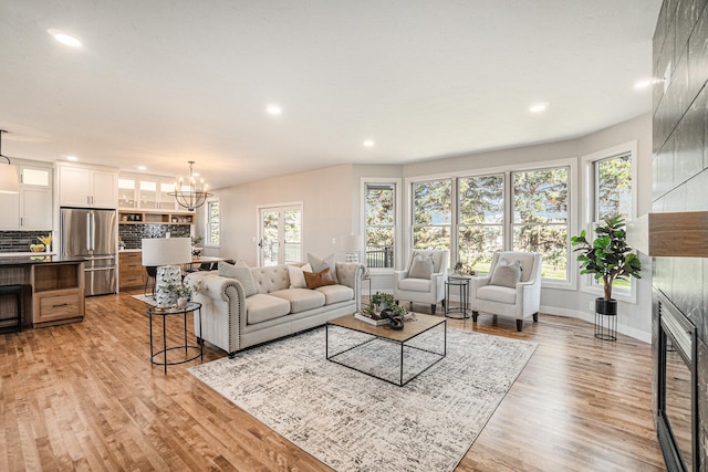 living room with a notable chandelier, light hardwood / wood-style floors, and a fireplace