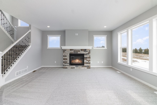 unfurnished living room featuring carpet flooring and a stone fireplace