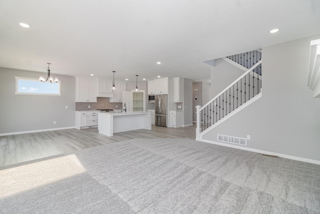 unfurnished living room with light carpet and an inviting chandelier