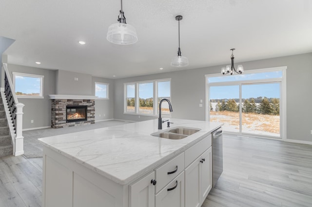 kitchen featuring dishwasher, pendant lighting, white cabinetry, and sink