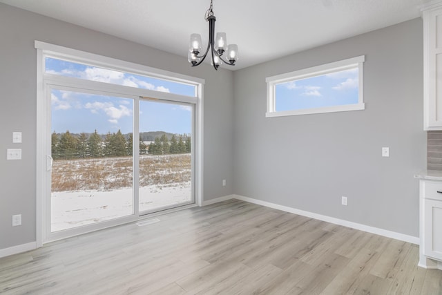 unfurnished dining area featuring light wood-type flooring and an inviting chandelier