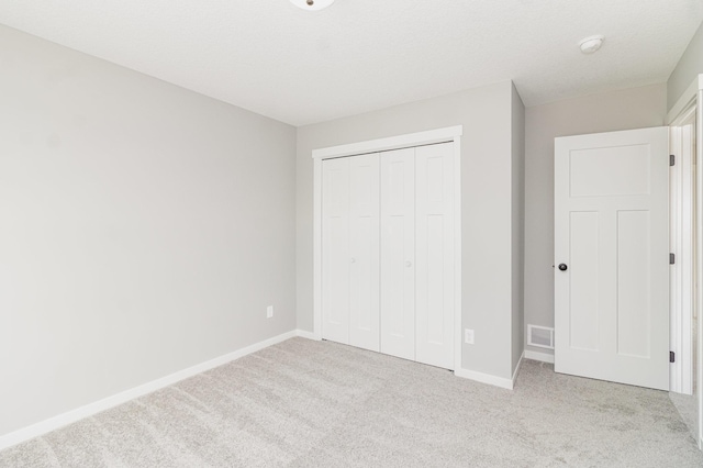 unfurnished bedroom featuring light carpet and a closet