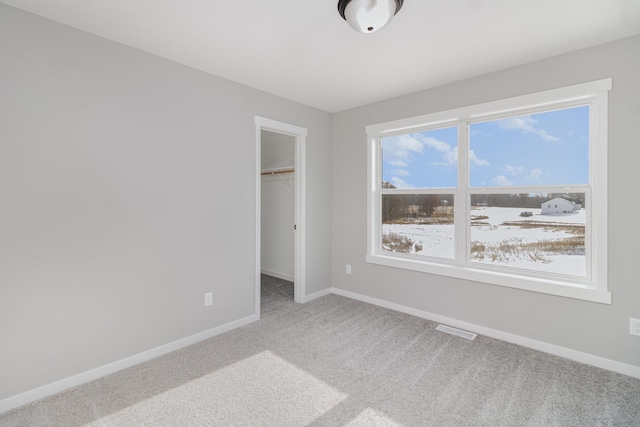 unfurnished bedroom with a walk in closet, a closet, and carpet