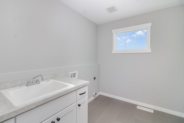 laundry room with cabinets, dark tile patterned flooring, sink, hookup for a washing machine, and hookup for an electric dryer