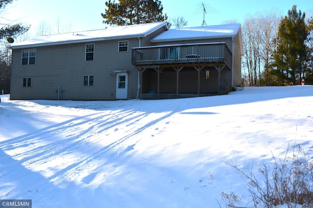 snow covered rear of property featuring a deck