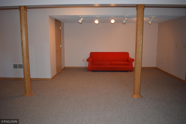 basement featuring rail lighting and light colored carpet