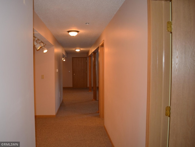 hall featuring a textured ceiling and light colored carpet