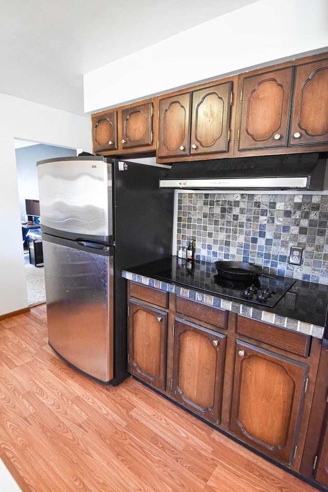 kitchen featuring tasteful backsplash, stainless steel refrigerator, and light hardwood / wood-style flooring