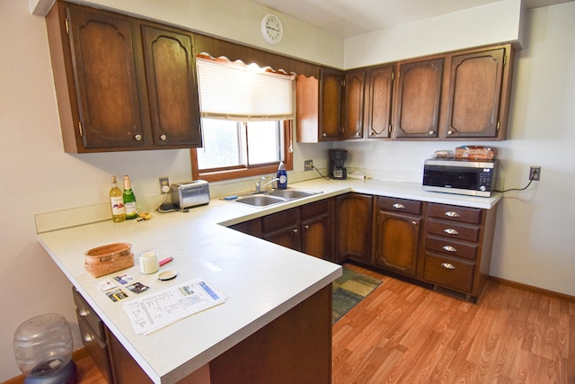 kitchen featuring kitchen peninsula, sink, dark brown cabinets, and light hardwood / wood-style flooring