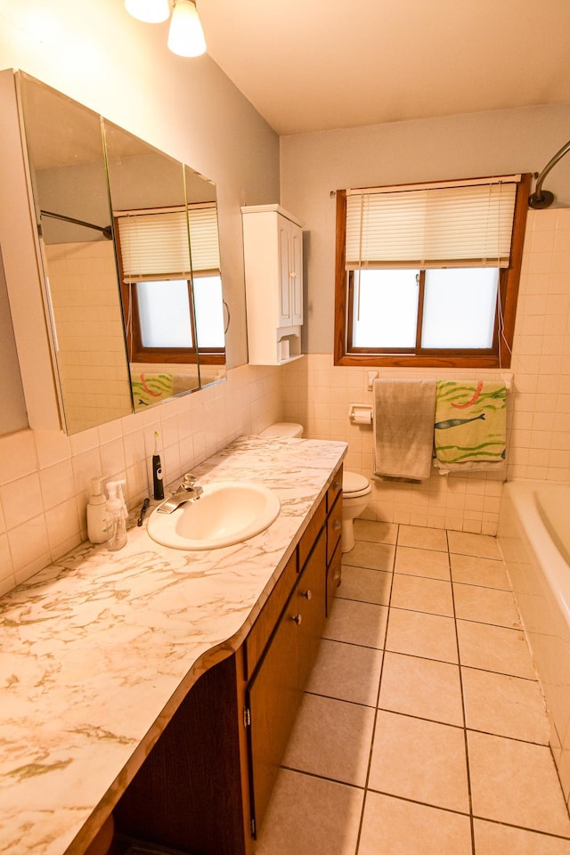 bathroom featuring tile patterned flooring, vanity, toilet, and tile walls