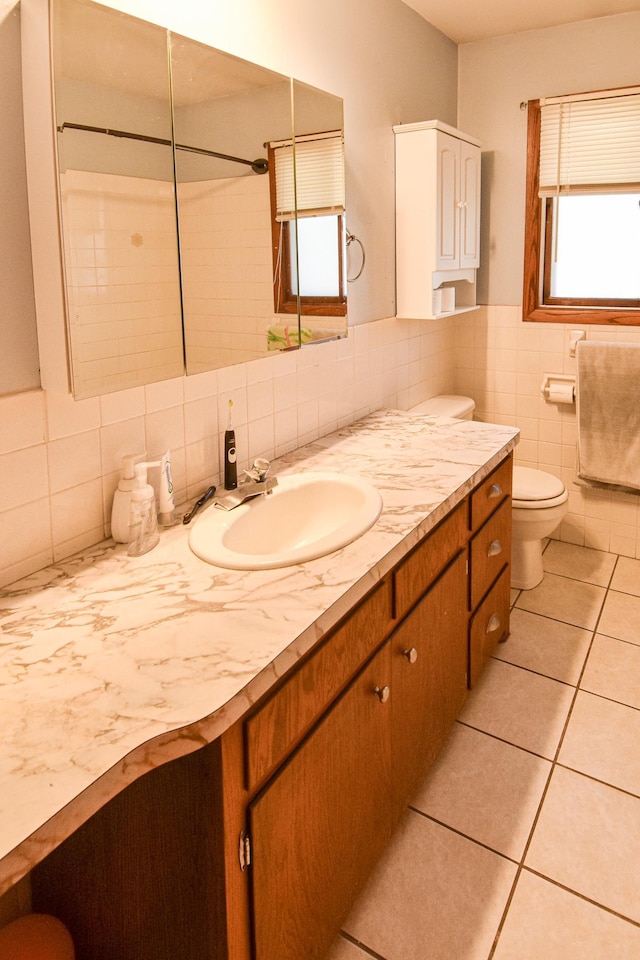 bathroom featuring tile patterned flooring, vanity, tile walls, and toilet