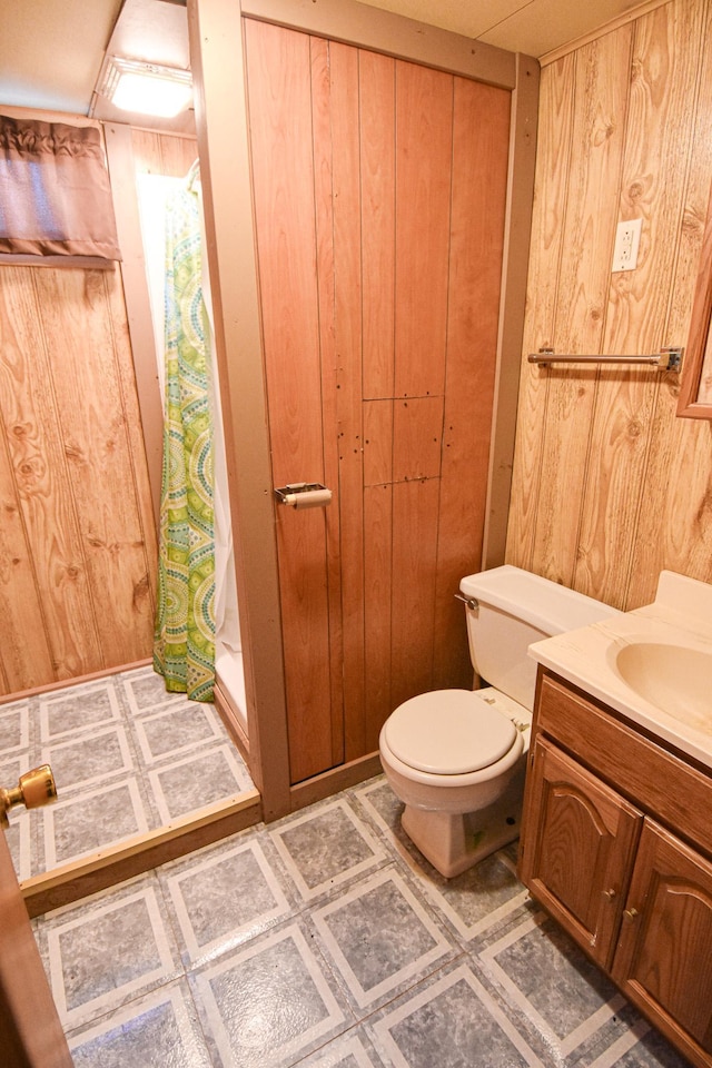 bathroom with vanity, toilet, curtained shower, and wood walls